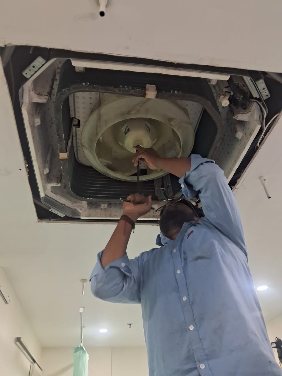 Technician servicing and repairing a ceiling cassette air conditioner unit